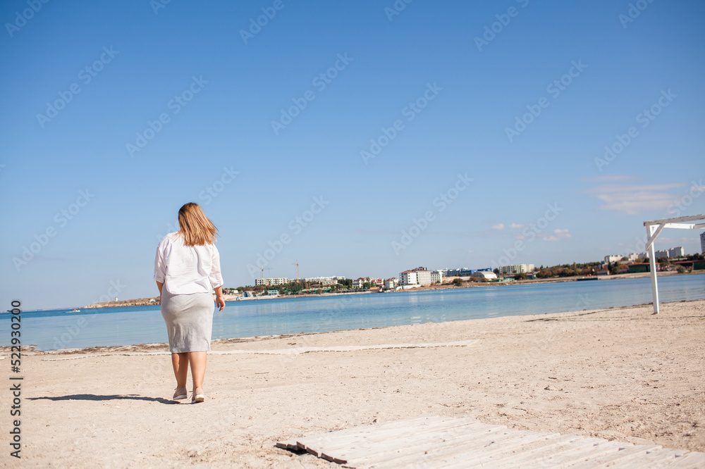 Pretty plus size woman walking in the beach against the sea, enjoy the time with her self, resting and love the nature