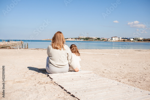 Happy family, mother and daughter have fun together in the sand beach against the sea or ocean . woman and kid spend time, happy people moments concept