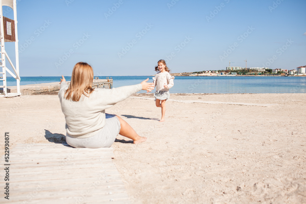 Happy family, mother and daughter have fun together in the sand beach against the sea or ocean . woman and kid spend time, happy people moments concept