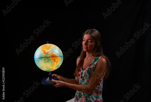 young woman observes the sphere of the world illuminated from within