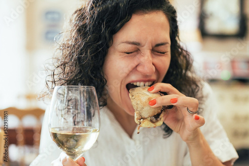 Woman with funny face biting a Portuguese meat sandwich 