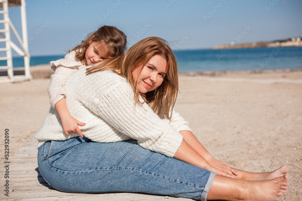 Happy family; mother and daughter have fun together in the sand beach against the sea or ocean . woman and kid spend time; happy people moments concept Happy family; mother and daughter have fun together in the sand beach against the sea or ocean . woman and kid spend time; happy people moments concept