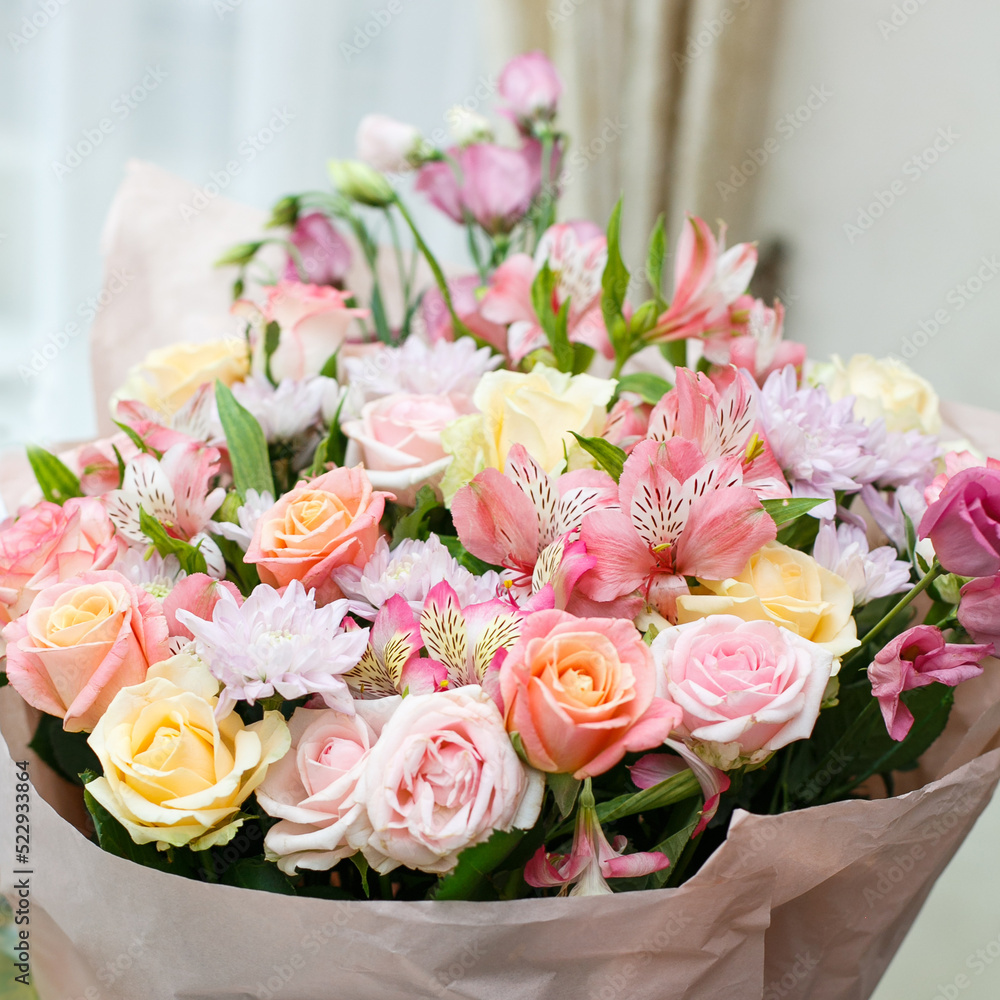 Large festive bouquet of fresh flowers made in pink stands on the table.