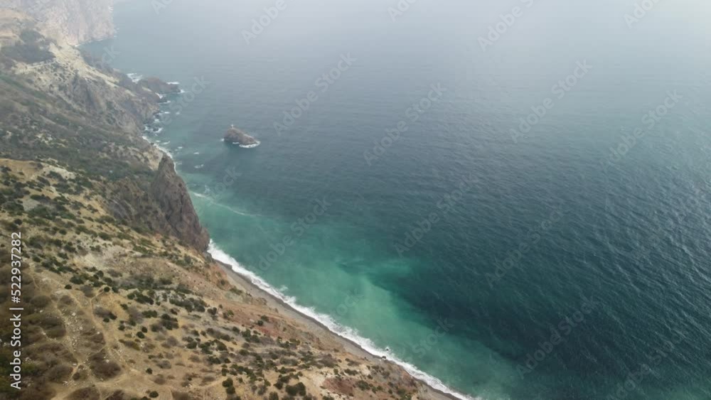 Aerial view from above on calm azure sea and volcanic rocky shores. Small waves on water surface in motion blur. Nature summer ocean sea beach background. Nobody. Holiday, vacation and travel concept Aerial view from above on calm azure sea and volcanic rocky shores. Small waves on water surface in motion blur. Nature summer ocean sea beach background. Nobody. Holiday, vacation and travel concept