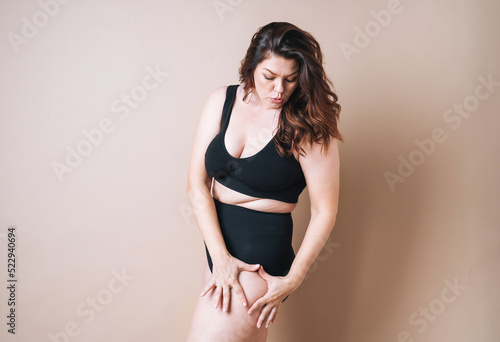 Portrait of self loving woman plus size in underwear on beige background, body love