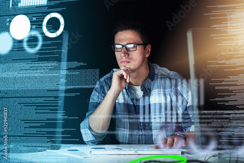 Male IT computer engineer working on a futuristic hologram or cgi screen at his office desk. Tech designer working on technology to test new and innovative data. Web developer work on a digital code photo