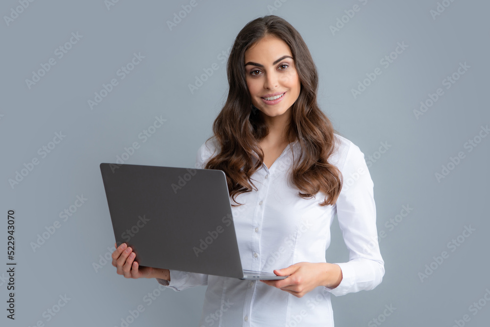 Portrait of a cheerful young casual girl standing isolated over gray background, using laptop computer. Business woman at work. Portrait of a cheerful young casual girl standing isolated over gray background, using laptop computer. Business woman at work.