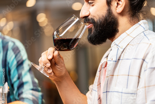leisure, drinks and people concept - close up of happy man with glass drinking red wine at restaurant
