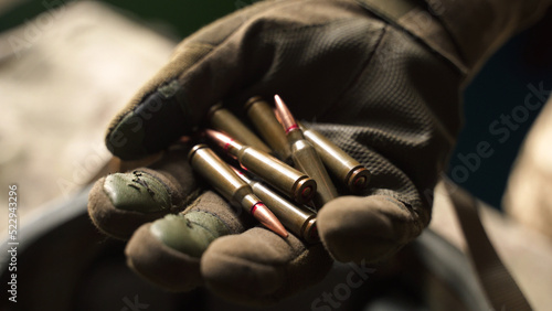 soldier holds bullets from his machine gun in his fist. old tactical glove. reloading of weapons  replenishment of military ammunition. protective equipment. preparation for a combat 