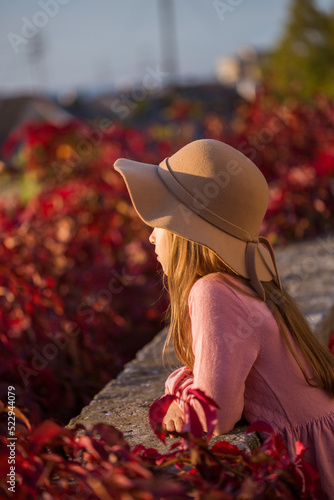 Girl wearing pink dress and hat walking in the autumn park  