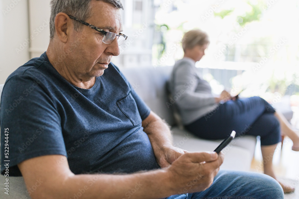 Senior couple using their mobile phones at home Senior couple using their mobile phones at home