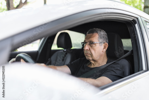 Senior in his 70s driving a car