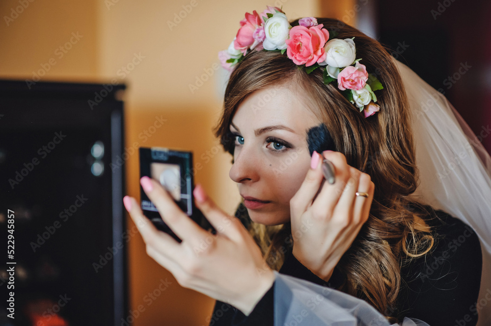 Fototapeta premium Beautiful girl doing makeup and holding make-up brush. Makeover. Perfect skin face. Applying Makeup. Bride with makeup and hairstyle, newlywed woman final preparation for wedding.