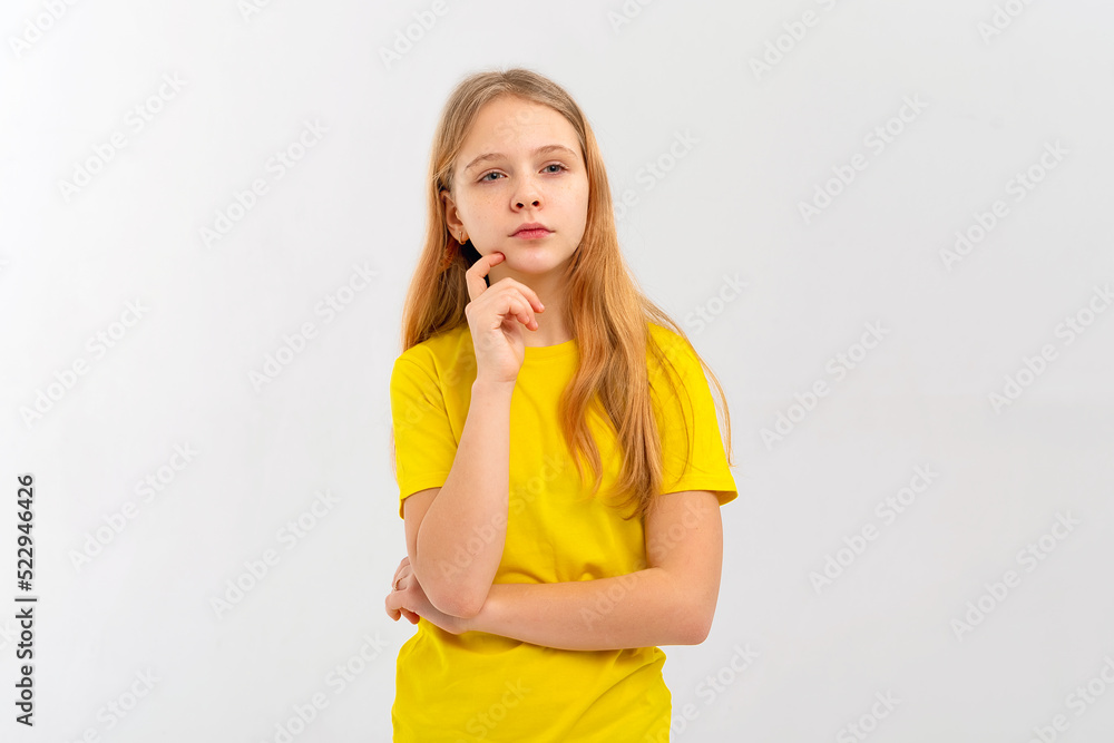 Dreamy nice pretty teen girl touch chin, thought choose decide solve problems dilemmas, wears yellow tshirt. Indoor studio shot on white background Dreamy nice pretty teen girl touch chin, thought choose decide solve problems dilemmas, wears yellow tshirt. Indoor studio shot on white background