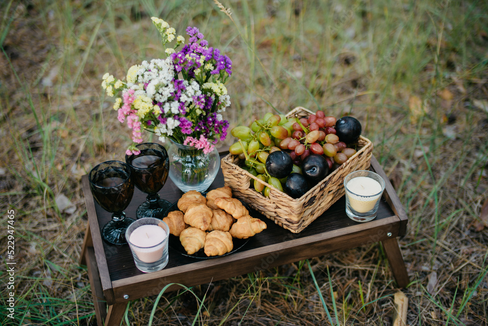 Romantic picnic in nature. Background fruits, croissants, wine, candles. Declaration of love. Romantic picnic in nature. Background fruits, croissants, wine, candles. Declaration of love.