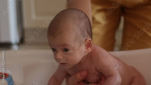 Mother bathing her newborn baby in a small bathtub