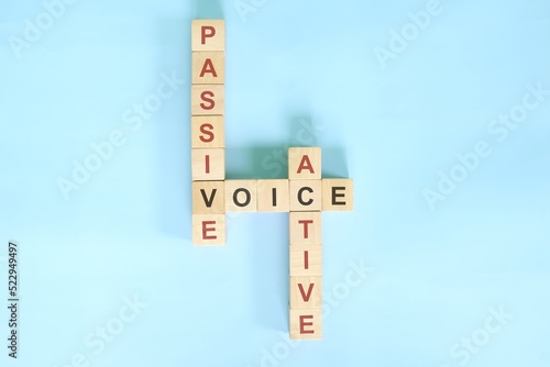 Obraz na płótnie Active and passive voice topic in English grammar teaching. Wooden block crossword puzzle flat lay in blue background. w salonie