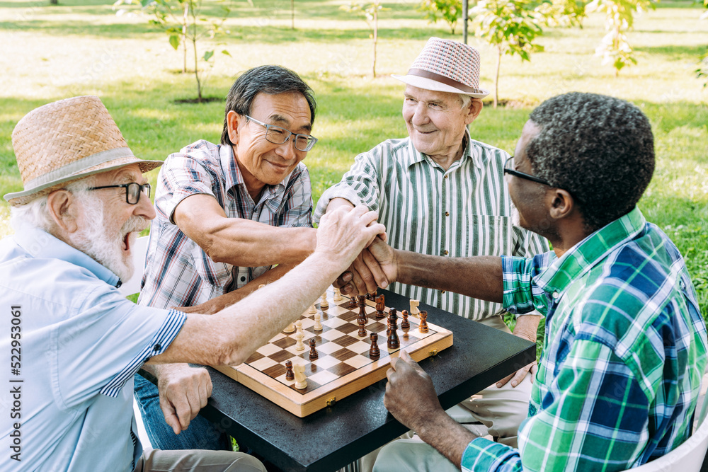 Group of senior friends playing chess at the park Group of senior friends playing chess at the park