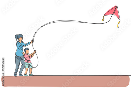 Single continuous line drawing of young mom and her son playing to fly kite up into the sky at outdoor field. Happy family parenthood concept. Trendy one line draw design vector graphic illustration