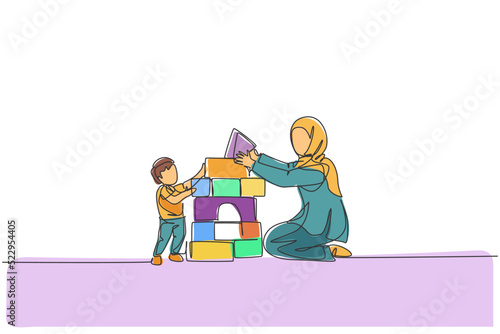 One continuous line drawing of young Arabian mother playing block foam puzzle brick with son. Happy Islamic muslim loving parenting family concept. Dynamic single line draw design vector illustration