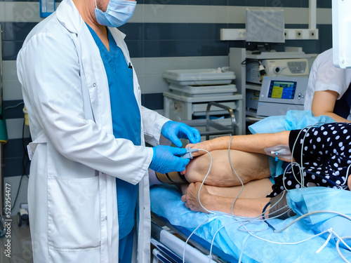 The doctor puts a pulse oximeter on the finger of an elderly woman. A doctor in a mask and gloves prepares a patient for a colonoscopy. An elderly woman undergoes an endoscopic examination. photo