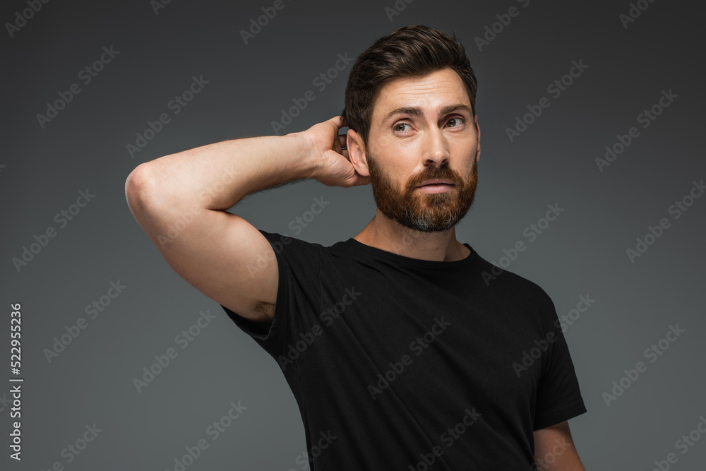portrait of puzzled man in black t-shirt looking away isolated on grey.