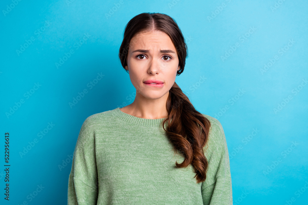 Photo of unsatisfied nice girl biting lips anxious worry look camera isolated on blue color background Photo of unsatisfied nice girl biting lips anxious worry look camera isolated on blue color background