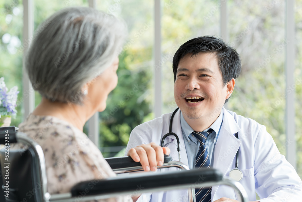 Male doctor and senior asian woman. Happy doctor taking care elderly asian woman on wheelchair at the hospital. People and health care concept Male doctor and senior asian woman. Happy doctor taking care elderly asian woman on wheelchair at the hospital. People and health care concept