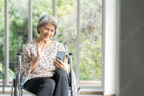 Elderly asian woman using mobile phone on wheelchair. Asian senior grandma use smart phone while sit on wheelchair at hospital