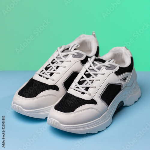 Close up of black and white fashionable sneakers on blue and green background.