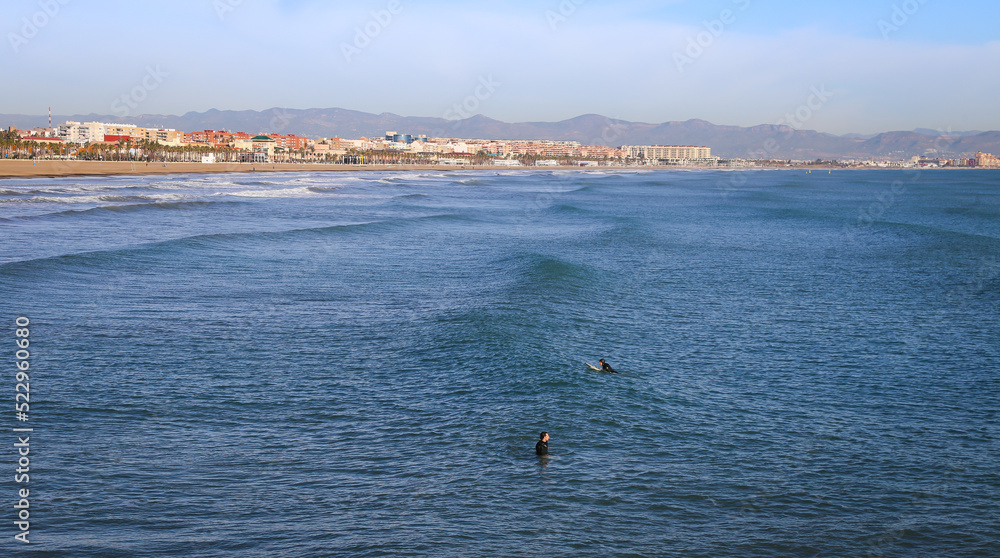 View of Valencia shoreline from a pier, with surfers in foreground