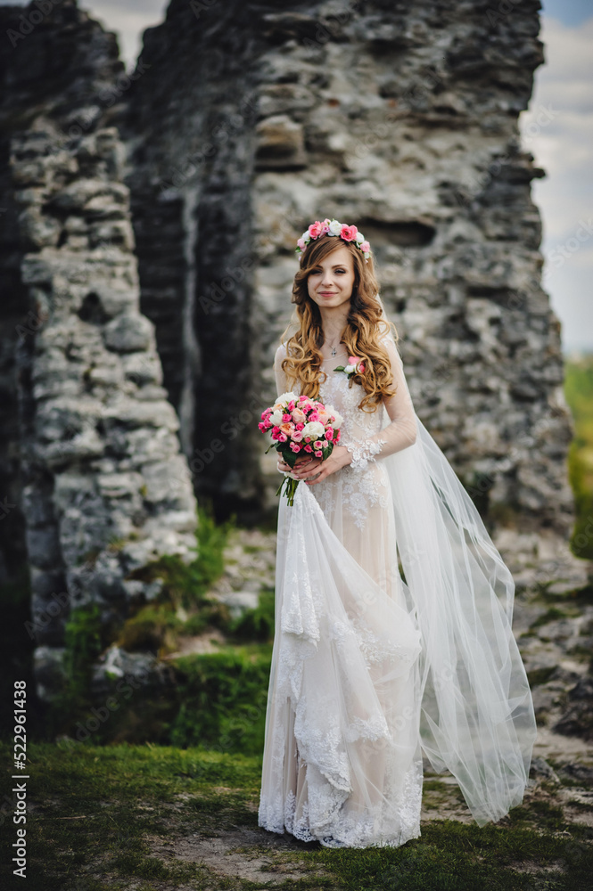 Young beautiful girl in elegant dress is standing and holding hand bouquet of pastel pink flowers and greens at nature. The bride holds a wedding bouquet outdoors. Young beautiful girl in elegant dress is standing and holding hand bouquet of pastel pink flowers and greens at nature. The bride holds a wedding bouquet outdoors.