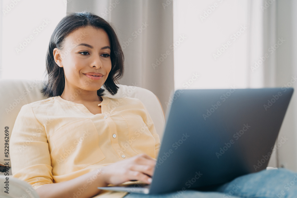 Female works at laptop sitting in chair at home office, shopping online. E-commerce, e-business Female works at laptop sitting in chair at home office, shopping online. E-commerce, e-business