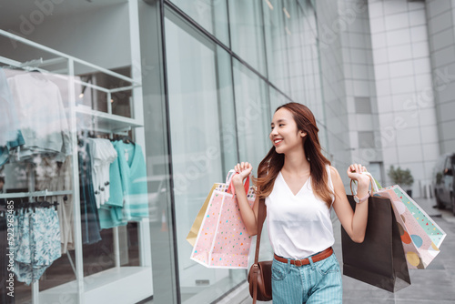 Beautiful asian female woman girl holding shopping bags, Walk enjoy smiling while doing shopping outside of department store malls window outdoors fashion lifestyle