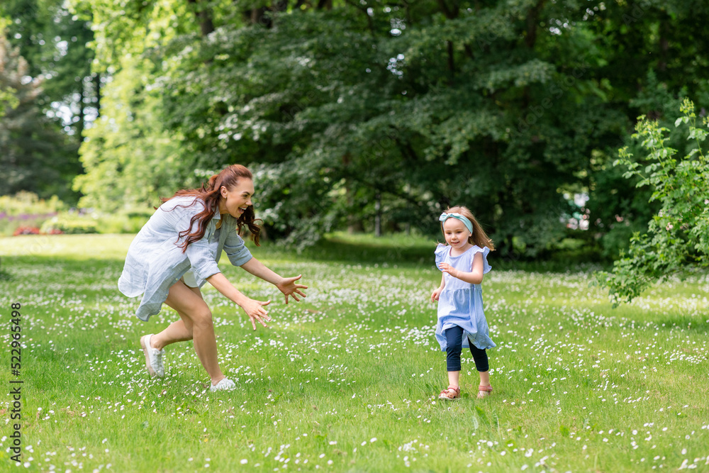 family, motherhood and people concept - happy mother with little daughter playing at summer park or garden