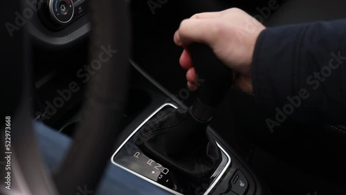 The hand switches the speed on the automatic transmission to the drive position. Close-up