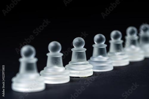 opaque glass chess pawn row on black background  selective focus  closeup