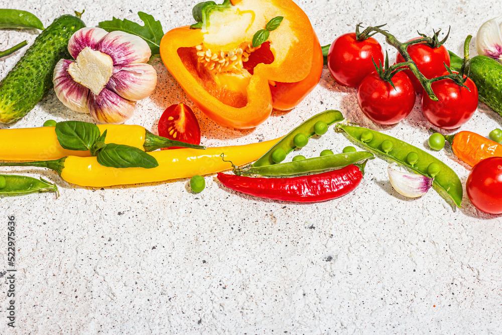 Assorted fresh vegetables and spices on light plaster background. Ripe yellow pepper, tomato, pea