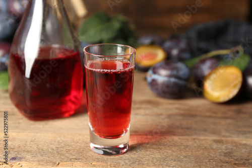 Delicious plum liquor on wooden table. Homemade strong alcoholic beverage