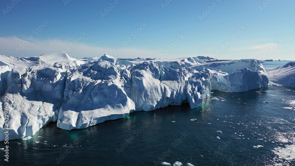 Aerial view from a drone of massive icebergs floating off the coast of a glacier on a sunny day in Disko Bay off the coast of Ilulissat, Greenland. Aerial view from a drone of massive icebergs floating off the coast of a glacier on a sunny day in Disko Bay off the coast of Ilulissat, Greenland.