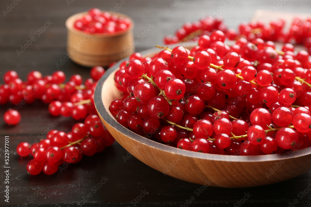 Delicious red currants in bowl on dark wooden table, closeup Delicious red currants in bowl on dark wooden table, closeup