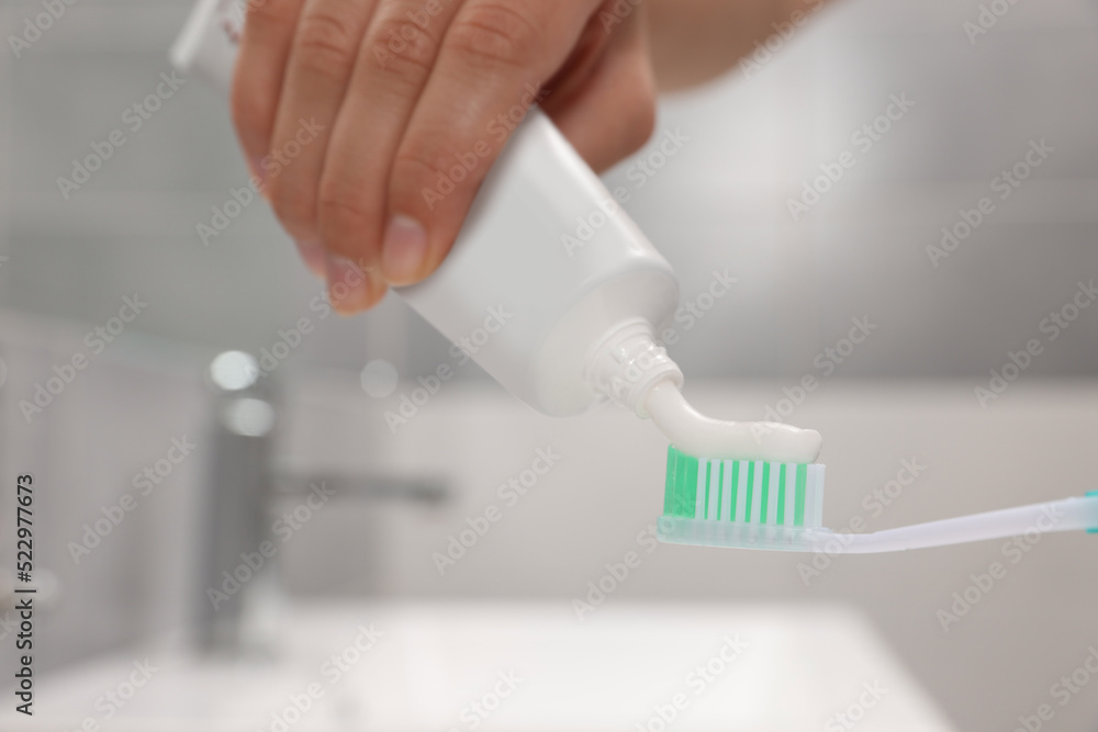 Woman applying toothpaste on brush in bathroom, closeup Woman applying toothpaste on brush in bathroom, closeup
