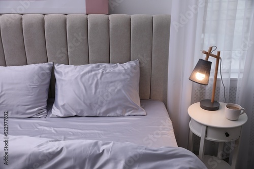 Cozy bed with soft silky bedclothes in light room