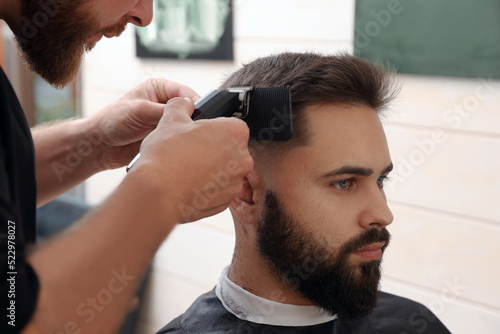 Professional hairdresser working with client in barbershop, closeup