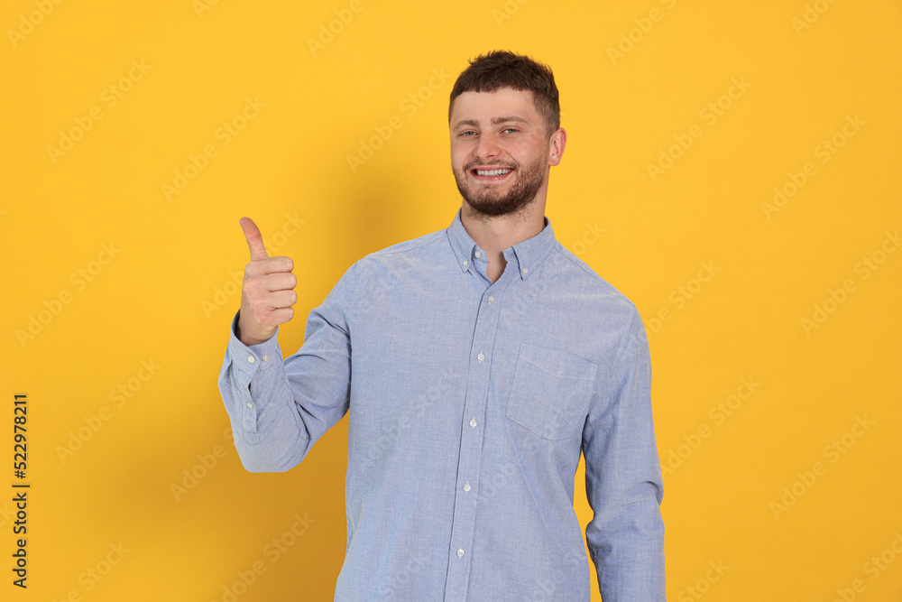 Young man showing thumb up on orange background Young man showing thumb up on orange background