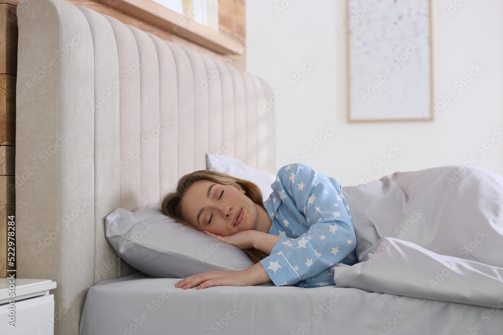 Young woman sleeping in comfortable bed with silky linens Young woman sleeping in comfortable bed with silky linens