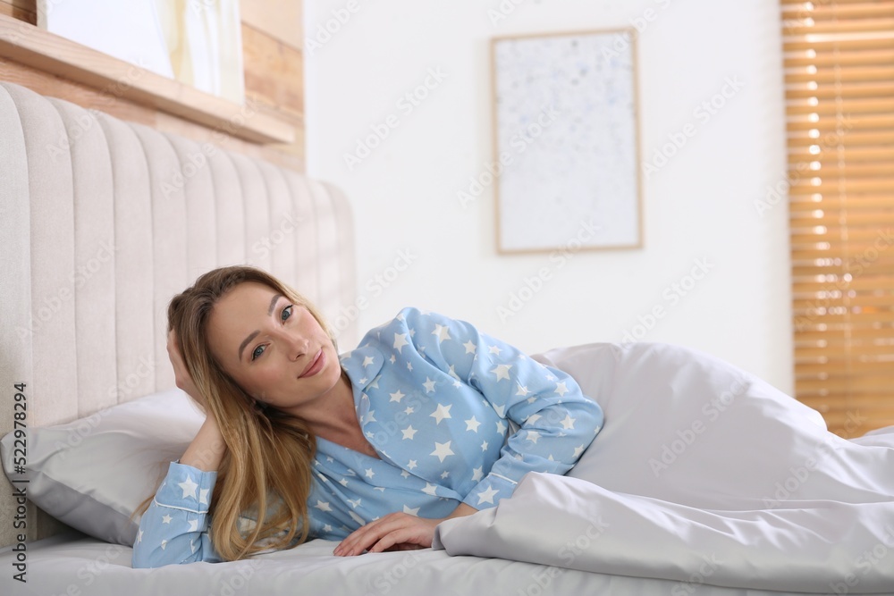 Young woman lying in comfortable bed with silky linens Young woman lying in comfortable bed with silky linens