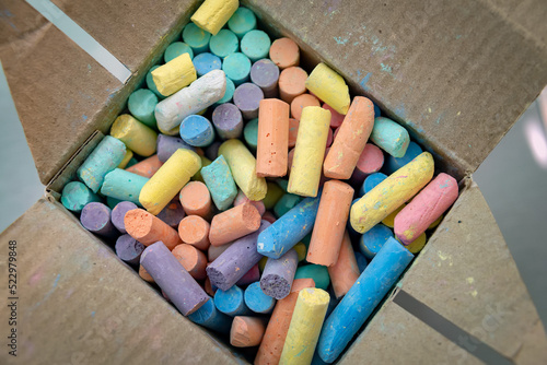 Many colorful chalks in a cardboard box. Top view