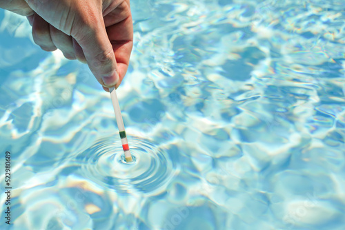 Checking the water quality of a pool with the help of a test strip with PH value, chlorine and algaecide