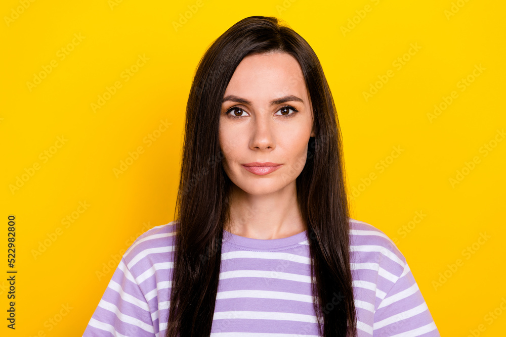 Photo of gorgeous confident positive girl dressed striped t-shirt seriously looking at camera isolated on yellow color background Photo of gorgeous confident positive girl dressed striped t-shirt seriously looking at camera isolated on yellow color background
